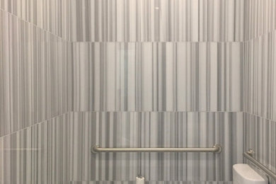 Modelo de cuarto de baño único y flotante actual pequeño con sanitario de dos piezas, baldosas y/o azulejos grises, baldosas y/o azulejos de mármol, paredes grises, suelo de mármol, aseo y ducha, lavabo suspendido y suelo gris