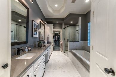 Inspiration for a large transitional master gray tile and stone tile marble floor and white floor bathroom remodel in Houston with recessed-panel cabinets, white cabinets, gray walls, an undermount sink and a hinged shower door