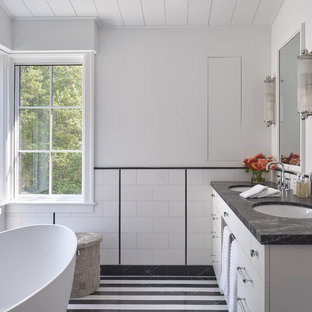 Example of a large arts and crafts master black and white tile, white tile and subway tile multicolored floor and porcelain tile bathroom design in San Francisco with flat-panel cabinets, white cabinets, an undermount sink, black countertops, a two-piece toilet, white walls, marble countertops and a hinged shower door
