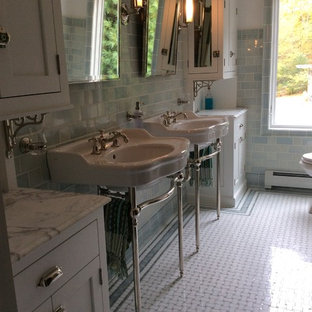 Elegant white tile and mosaic tile mosaic tile floor bathroom photo in New York with a pedestal sink, furniture-like cabinets, white cabinets, marble countertops and white walls