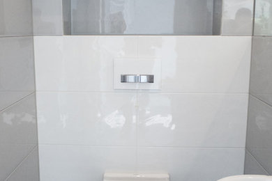 Diseño de cuarto de baño moderno pequeño con lavabo suspendido, armarios con paneles lisos, puertas de armario blancas, encimera de laminado, sanitario de pared, baldosas y/o azulejos grises, baldosas y/o azulejos de cerámica, paredes blancas, suelo de baldosas de cerámica y aseo y ducha