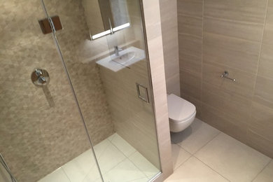 Inspiration for a medium sized contemporary ensuite bathroom in Essex with a wall mounted toilet, beige tiles, porcelain tiles, beige walls and porcelain flooring.
