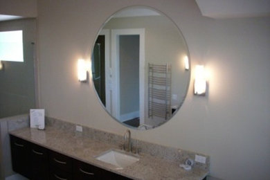 Foto de cuarto de baño de tamaño medio con lavabo integrado, armarios con paneles lisos, puertas de armario de madera en tonos medios, encimera de granito, paredes blancas y aseo y ducha