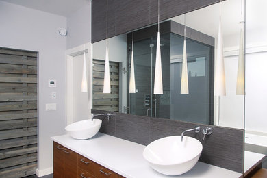 Bathroom - mid-sized contemporary master gray tile and porcelain tile porcelain tile and gray floor bathroom idea in Edmonton with a vessel sink, flat-panel cabinets, gray walls, solid surface countertops, medium tone wood cabinets, a hinged shower door and white countertops
