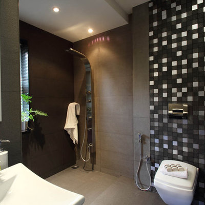 Trendy gray tile and stone tile concrete floor walk-in shower photo in Bengaluru with a wall-mount toilet and gray walls