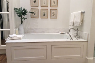 Inspiration for a large classic ensuite bathroom in Other with beaded cabinets, white cabinets, a submerged bath, white tiles, white walls, medium hardwood flooring, marble worktops, brown floors and white worktops.