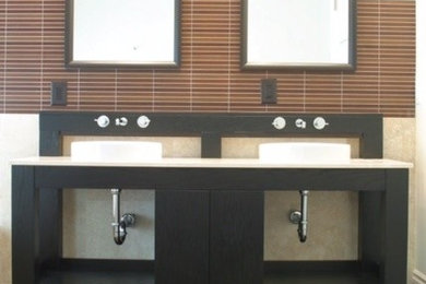 Mid-sized minimalist 3/4 light wood floor corner shower photo in Miami with furniture-like cabinets, black cabinets, a one-piece toilet, beige walls, quartzite countertops and a vessel sink