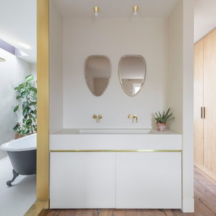 This is an example of a medium sized modern ensuite bathroom in Cheshire with flat-panel cabinets, white cabinets, a claw-foot bath, white walls, medium hardwood flooring, a submerged sink, brown floors and white worktops.