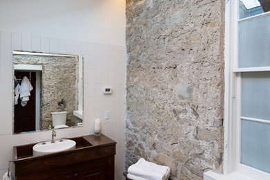Bild på ett mellanstort amerikanskt en-suite badrum, med luckor med upphöjd panel, skåp i mörkt trä, en kantlös dusch, svart kakel, vit kakel, vita väggar, klinkergolv i keramik, ett fristående handfat, träbänkskiva och tunnelbanekakel