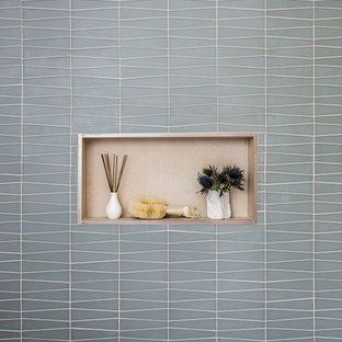 Example of a small trendy green tile and ceramic tile ceramic tile and white floor bathroom design in San Francisco with flat-panel cabinets, beige cabinets, white walls, a wall-mount sink, solid surface countertops, a one-piece toilet and white countertops