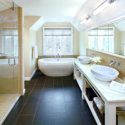 Elegant yellow tile black floor freestanding bathtub photo in Minneapolis with a vessel sink and beige walls