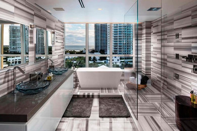 Example of a large minimalist master marble floor bathroom design in Miami with flat-panel cabinets, white cabinets, gray walls, a vessel sink and solid surface countertops