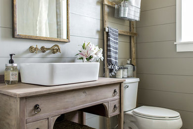 Aménagement d'une petite salle de bain principale et beige et blanche campagne en bois clair avec une baignoire sur pieds, une vasque, WC séparés, un mur gris, carreaux de ciment au sol, un sol noir, un plan de toilette marron et un placard à porte plane.