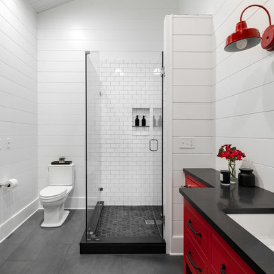 Example of a large cottage white tile and subway tile slate floor and gray floor corner shower design in New York with flat-panel cabinets, red cabinets, a two-piece toilet, white walls, an undermount sink, concrete countertops, black countertops and a hinged shower door
