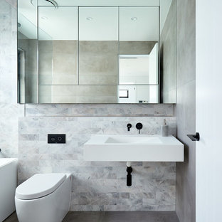 Photo of a contemporary bathroom in Sydney with an alcove tub, gray tile, an integrated sink, grey floor and white benchtops.