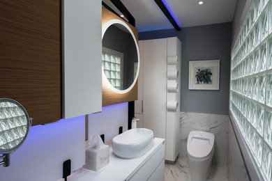 Example of a small minimalist master white tile and porcelain tile porcelain tile and white floor bathroom design in Charlotte with flat-panel cabinets, white cabinets, a bidet, gray walls, a vessel sink, solid surface countertops and white countertops