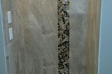 Example of a mid-sized minimalist beige tile and pebble tile alcove shower design in Other