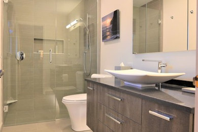 Example of a small minimalist master gray tile and porcelain tile porcelain tile and gray floor walk-in shower design in Chicago with flat-panel cabinets, medium tone wood cabinets, a one-piece toilet, white walls, a vessel sink, quartz countertops and a hinged shower door