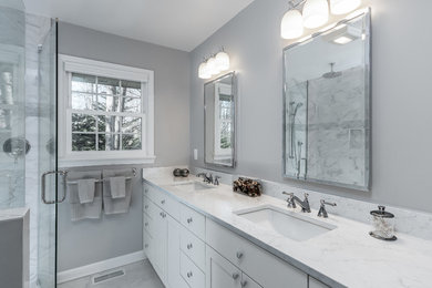 Mid-sized transitional master marble tile and gray tile marble floor and gray floor double shower photo in Raleigh with shaker cabinets, white cabinets, a one-piece toilet, gray walls, an undermount sink, marble countertops, a hinged shower door and white countertops