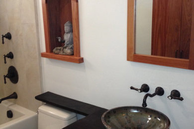 Imagen de cuarto de baño de estilo zen con lavabo sobreencimera, bañera empotrada, bidé, armarios tipo mueble, puertas de armario de madera en tonos medios y encimera de madera