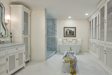 Example of a large beach style master marble floor and white floor bathroom design in Miami with furniture-like cabinets, white cabinets, beige walls, an undermount sink, marble countertops, a hinged shower door and white countertops
