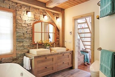 Example of a large cottage master beige tile and stone tile porcelain tile and brown floor freestanding bathtub design in Jacksonville with medium tone wood cabinets, a one-piece toilet, white walls, a vessel sink, marble countertops, beige countertops and shaker cabinets