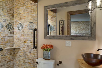 Example of a small mountain style 3/4 beige tile and porcelain tile porcelain tile doorless shower design in Phoenix with furniture-like cabinets, light wood cabinets, a one-piece toilet, beige walls, a vessel sink, wood countertops and brown countertops