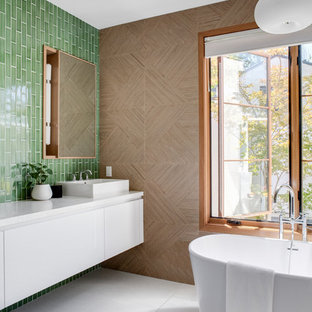 Inspiration för ett mellanstort funkis vit vitt en-suite badrum, med släta luckor, vita skåp, ett fristående badkar, grön kakel, bruna väggar, ett fristående handfat, en toalettstol med hel cisternkåpa, bänkskiva i kvartsit, keramikplattor, cementgolv och grått golv