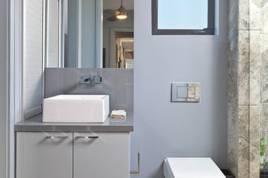 Idée de décoration pour une salle de bain principale minimaliste de taille moyenne avec des portes de placard grises, WC suspendus et un mur bleu.