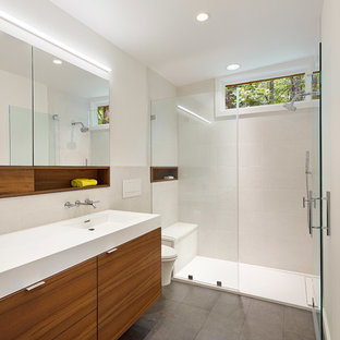 Aménagement d'une petit salle de bain principale moderne avec un placard à porte plane, des portes de placard marrons, une douche à l'italienne, un WC suspendu, un carrelage jaune, des carreaux de porcelaine, un mur blanc, un sol en carrelage de porcelaine, un lavabo intégré, un plan de toilette en surface solide, un sol gris et une cabine de douche à porte battante.