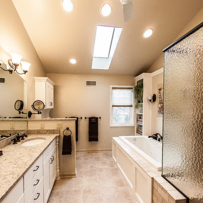 Bathroom - mid-sized traditional master beige tile and porcelain tile porcelain tile and brown floor bathroom idea in Other with an undermount sink, white cabinets, flat-panel cabinets, a one-piece toilet, white walls, quartz countertops and a hinged shower door