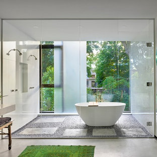 Diseño de cuarto de baño principal, moderno, de tamaño medio, con bañera exenta, ducha con puerta con bisagras, ducha doble, baldosas y/o azulejos blancos, paredes blancas, suelo de cemento y suelo gris