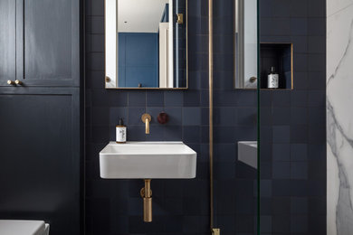 Modelo de cuarto de baño principal, único y flotante actual de tamaño medio con ducha abierta, baldosas y/o azulejos azules y lavabo suspendido