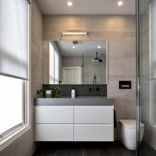 Photo of a mid-sized contemporary 3/4 bathroom in Melbourne with white cabinets, a wall-mount toilet, gray tile, porcelain tile, an integrated sink, black floor, grey benchtops, a single vanity and a floating vanity.