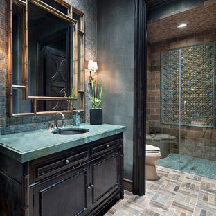 Photo of a mediterranean 3/4 bathroom in Houston with furniture-like cabinets, dark wood cabinets, a curbless shower, blue tile, brown tile, green tile, mosaic tile, green walls, mosaic tile floors, an undermount sink, beige floor, a hinged shower door and turquoise benchtops.