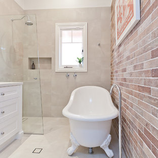 This is an example of a mid-sized transitional master bathroom in Perth with shaker cabinets, white cabinets, a claw-foot tub, a curbless shower, subway tile, beige walls, porcelain floors, an undermount sink, engineered quartz benchtops, beige floor, a hinged shower door, white benchtops and red tile.