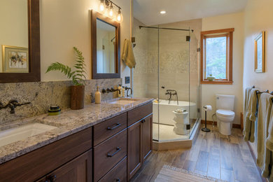 Inspiration for a mid-sized contemporary master beige tile and pebble tile dark wood floor and gray floor bathroom remodel with shaker cabinets, medium tone wood cabinets, a one-piece toilet, beige walls, an undermount sink, granite countertops and a hinged shower door