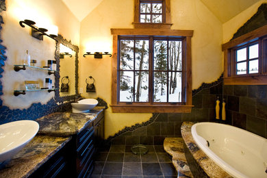 Mid-sized mountain style master black tile and slate tile slate floor and black floor drop-in bathtub photo in Denver with recessed-panel cabinets, black cabinets, yellow walls, a vessel sink, granite countertops and multicolored countertops