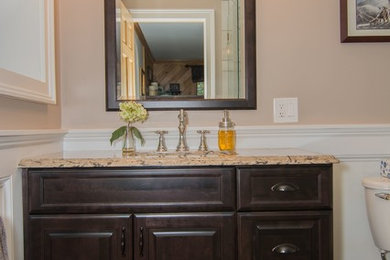 Example of a small classic 3/4 beige tile and porcelain tile porcelain tile and beige floor corner shower design in Portland Maine with raised-panel cabinets, brown cabinets, a two-piece toilet, beige walls, an undermount sink, quartz countertops and a hinged shower door