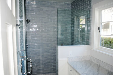Modelo de cuarto de baño clásico con lavabo bajoencimera, armarios con paneles empotrados, puertas de armario blancas, encimera de mármol, ducha empotrada, baldosas y/o azulejos blancos y baldosas y/o azulejos de cerámica