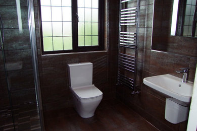 This is an example of a medium sized contemporary family bathroom in Other with a wall-mounted sink, a walk-in shower, a two-piece toilet, brown tiles, porcelain tiles, brown walls and porcelain flooring.