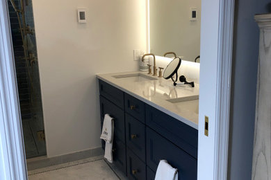 Mid-sized minimalist blue tile and porcelain tile marble floor, gray floor and double-sink bathroom photo in New York with recessed-panel cabinets, blue cabinets, a one-piece toilet, white walls, an undermount sink, quartz countertops, a hinged shower door, gray countertops and a built-in vanity