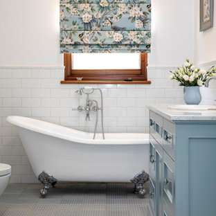 This is an example of a traditional 3/4 bathroom in Adelaide with recessed-panel cabinets, blue cabinets, a claw-foot tub, white tile, subway tile, white walls, a drop-in sink, grey floor, grey benchtops and a single vanity.