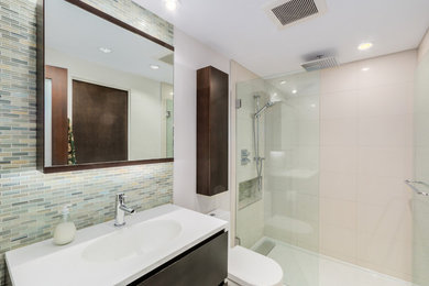 Bathroom - small modern 3/4 multicolored tile and glass tile porcelain tile bathroom idea in Vancouver with flat-panel cabinets, dark wood cabinets, a one-piece toilet, white walls, an integrated sink and solid surface countertops