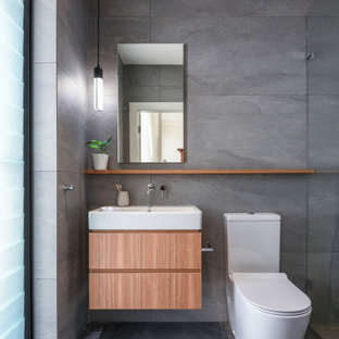 Inspiration for a mid-sized contemporary 3/4 bathroom in Sydney with flat-panel cabinets, medium wood cabinets, gray tile, ceramic tile, ceramic floors, grey floor, an open shower, a curbless shower, a two-piece toilet and a console sink.