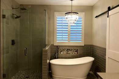 Идея дизайна: главная ванная комната среднего размера в стиле неоклассика (современная классика) с отдельно стоящей ванной, угловым душем, серой плиткой, керамогранитной плиткой, серыми стенами, полом из керамогранита, серым полом, открытым душем, фасадами с утопленной филенкой, серыми фасадами, серой столешницей, раздельным унитазом, врезной раковиной и столешницей из искусственного кварца