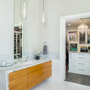 Imagen de cuarto de baño principal, actual, con armarios con paneles lisos, puertas de armario de madera oscura, encimera de mármol, baldosas y/o azulejos blancos, lavabo bajoencimera y paredes grises