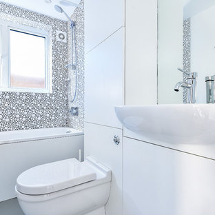 Design ideas for a small contemporary family bathroom in London with flat-panel cabinets, white cabinets, a built-in bath, a built-in shower, a one-piece toilet, white tiles, ceramic tiles, white walls, lino flooring, an integrated sink, laminate worktops, grey floors, a shower curtain and white worktops.