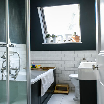Transitional drop-in bathtub photo in London with an integrated sink, black cabinets and black walls
