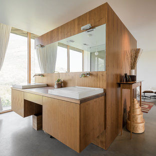 Imagen de cuarto de baño contemporáneo con armarios con paneles lisos, puertas de armario de madera oscura, paredes blancas, suelo de cemento y lavabo sobreencimera
